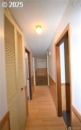 corridor featuring light wood-style floors and wainscoting