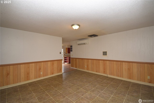 unfurnished room with a wainscoted wall, a textured ceiling, an AC wall unit, and wood walls