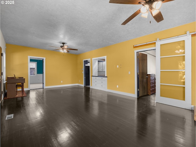 682 S Settlemier Ave, Woodburn, OR 97071 - unfurnished living room with ceiling fan, a barn door, a textured ceiling, wood finished floors, and baseboards