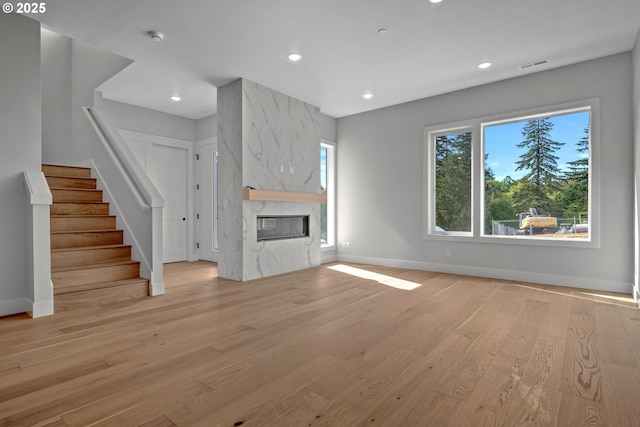 unfurnished living room with a high end fireplace and light wood-type flooring