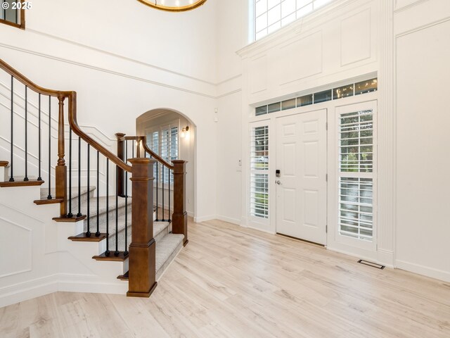 foyer with a healthy amount of sunlight, light wood-type flooring, and a high ceiling