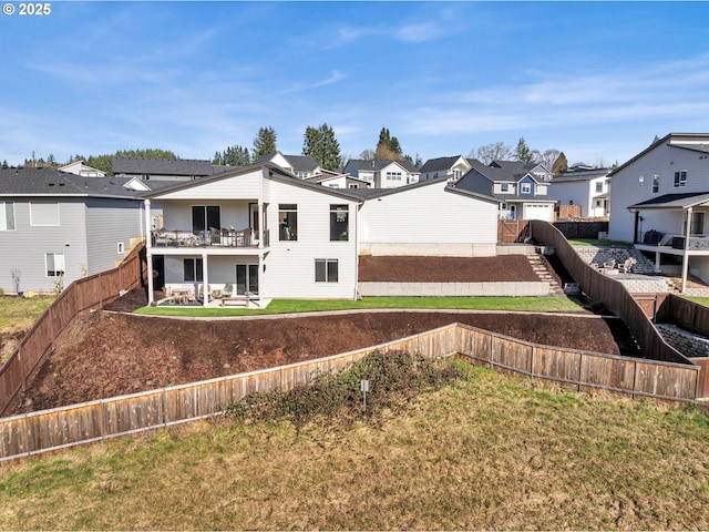 rear view of house featuring a balcony, a lawn, a fenced backyard, and a residential view