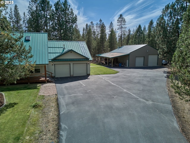 view of front of house with a front yard, metal roof, an attached garage, and driveway