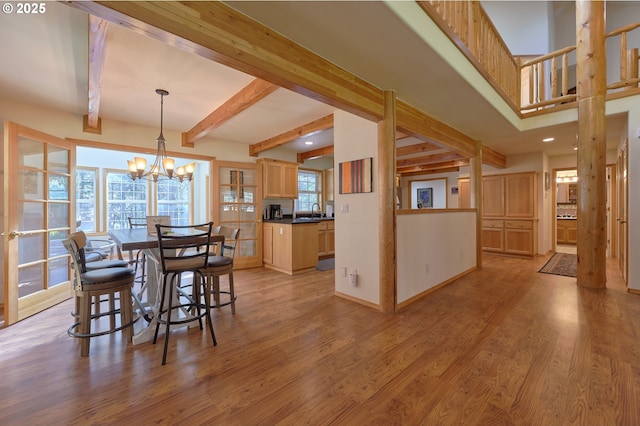dining room with light wood finished floors, a chandelier, beam ceiling, recessed lighting, and baseboards