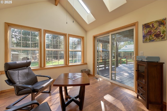 sitting room featuring a skylight, wood finished floors, healthy amount of natural light, beam ceiling, and high vaulted ceiling