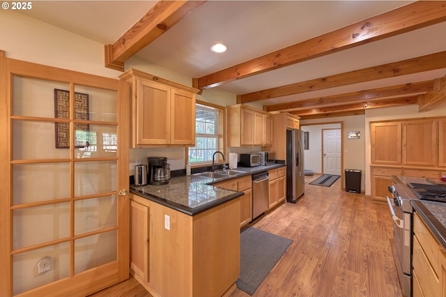kitchen with stainless steel appliances, a sink, beamed ceiling, light brown cabinetry, and dark countertops