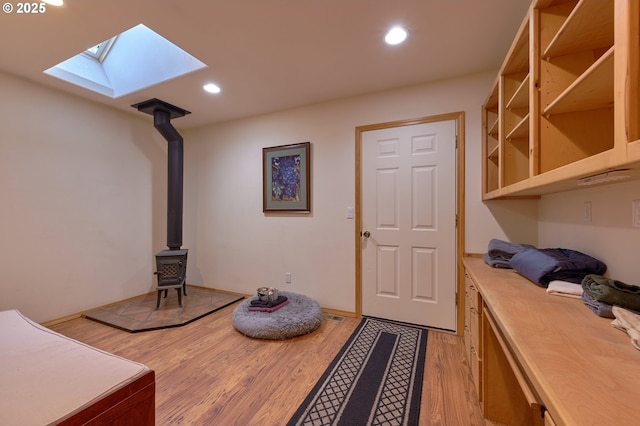 entrance foyer featuring a skylight, a wood stove, light wood-style flooring, and recessed lighting