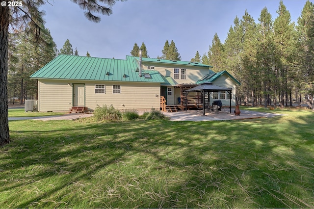 rear view of house with a gazebo, entry steps, metal roof, a lawn, and central air condition unit