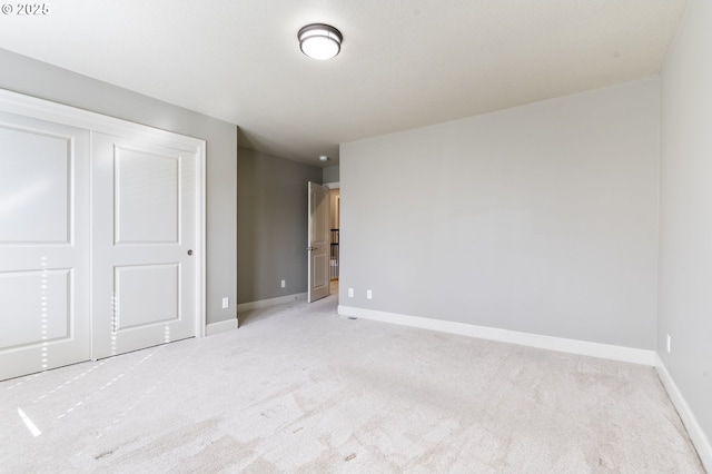 unfurnished bedroom with baseboards, a closet, and light colored carpet