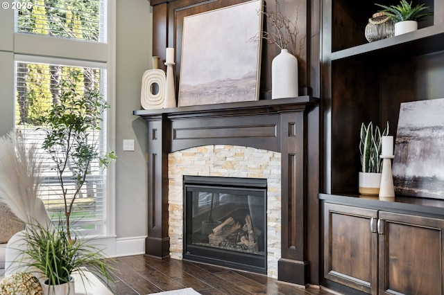 interior details featuring a stone fireplace, baseboards, and wood finished floors