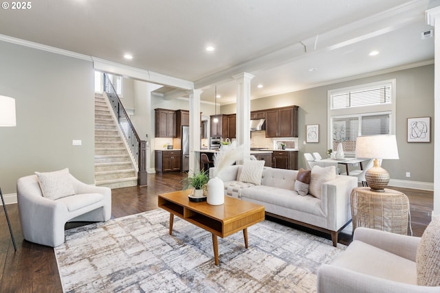 living room featuring ornate columns, stairway, dark wood-type flooring, and ornamental molding