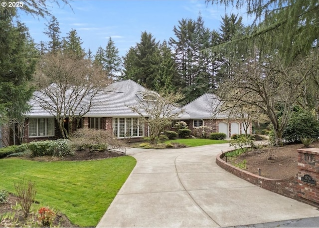 view of front of property featuring brick siding, a front lawn, and driveway