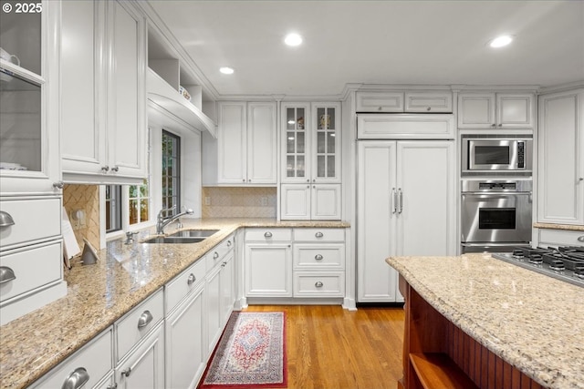 kitchen with built in appliances, light hardwood / wood-style floors, light stone countertops, and white cabinetry