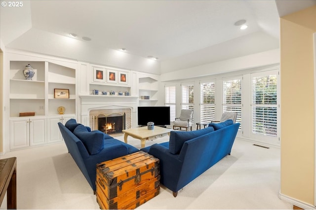 carpeted living room featuring vaulted ceiling, built in features, and a tray ceiling