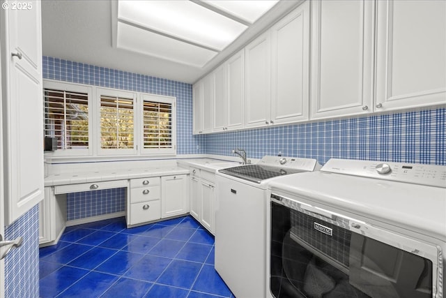 clothes washing area with dark tile patterned flooring, cabinets, sink, and washing machine and clothes dryer