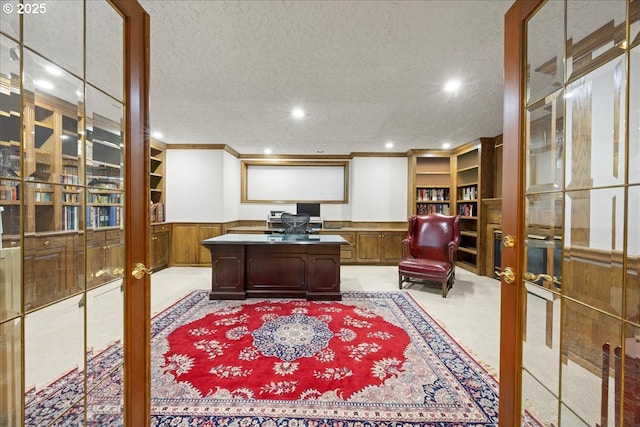 carpeted home office featuring french doors and a textured ceiling