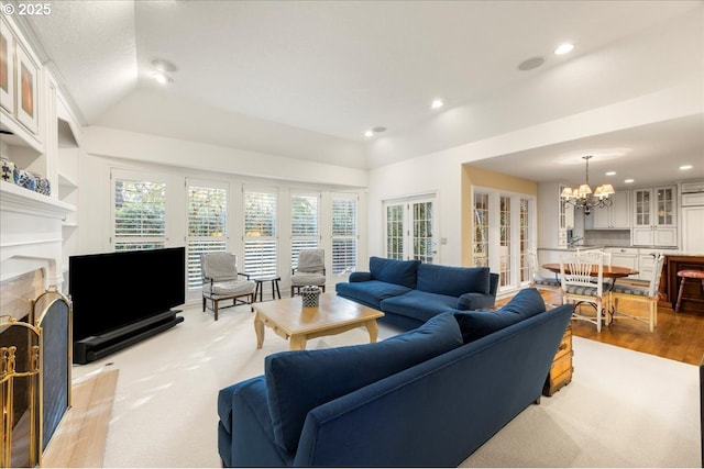 living room with light wood-type flooring, lofted ceiling, a wealth of natural light, and a chandelier