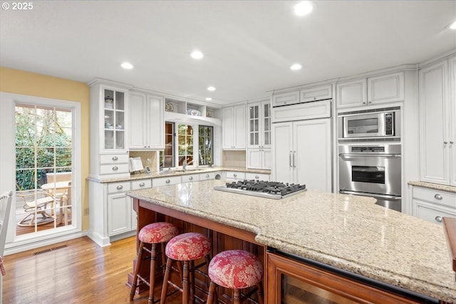 kitchen with tasteful backsplash, sink, built in appliances, white cabinets, and a breakfast bar area