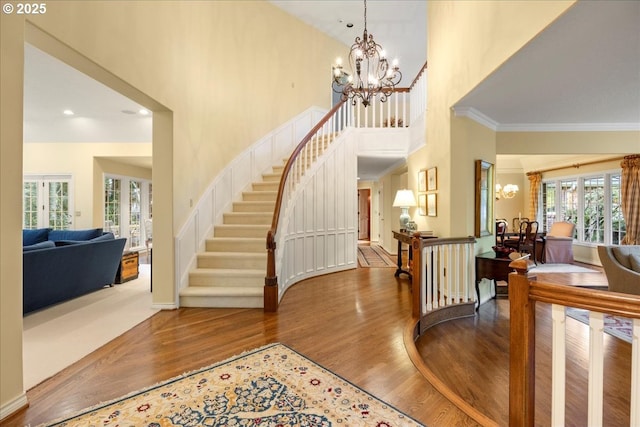 foyer entrance featuring wood-type flooring, crown molding, and a chandelier