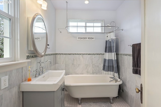 bathroom featuring a washtub, vanity, tile patterned flooring, and tile walls