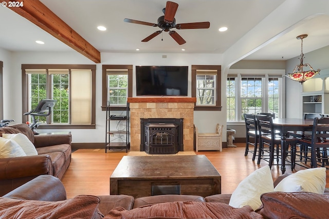 living room with beamed ceiling, ceiling fan, plenty of natural light, and light wood-type flooring