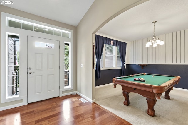 foyer entrance with hardwood / wood-style flooring, vaulted ceiling, billiards, and a chandelier