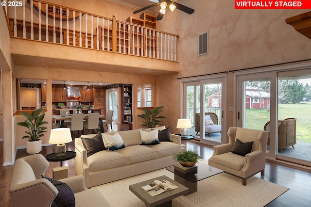 living room featuring visible vents, a high ceiling, a ceiling fan, and wood finished floors