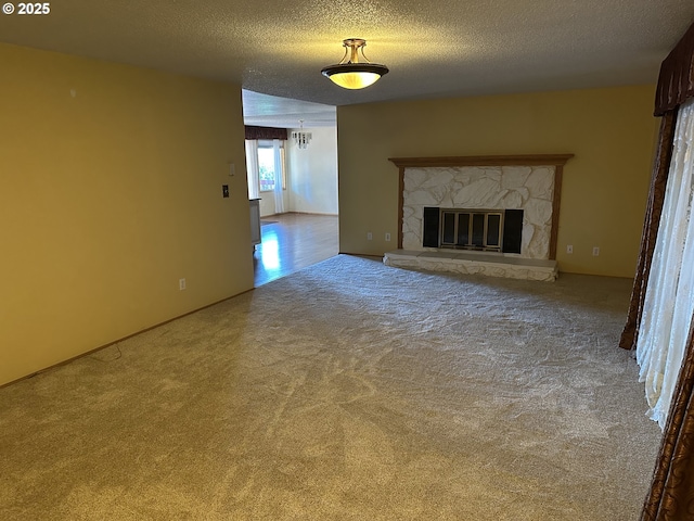 unfurnished living room featuring carpet floors, a fireplace, and a textured ceiling