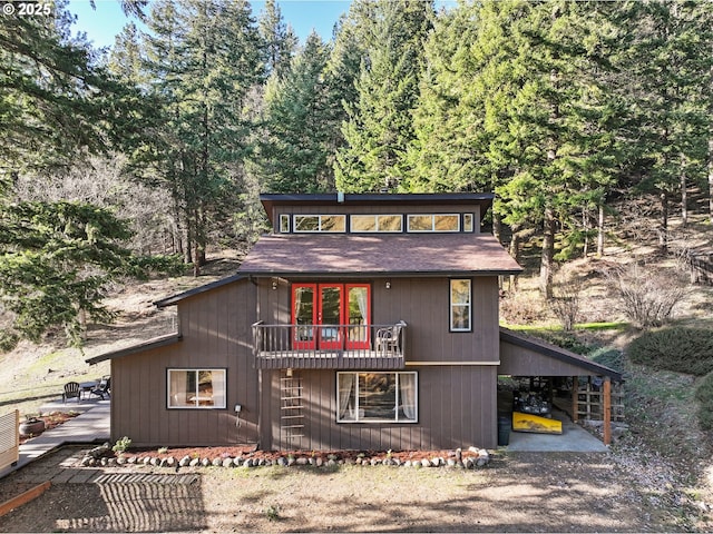 rear view of property with gravel driveway, an attached carport, and a deck