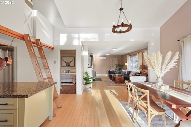 dining area with a notable chandelier, an AC wall unit, and light wood-style floors