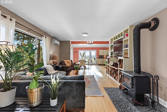 living room featuring a wood stove, wood-type flooring, baseboards, and a wall mounted air conditioner