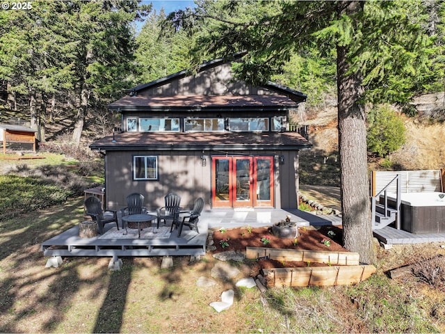 rear view of property featuring a hot tub and a deck