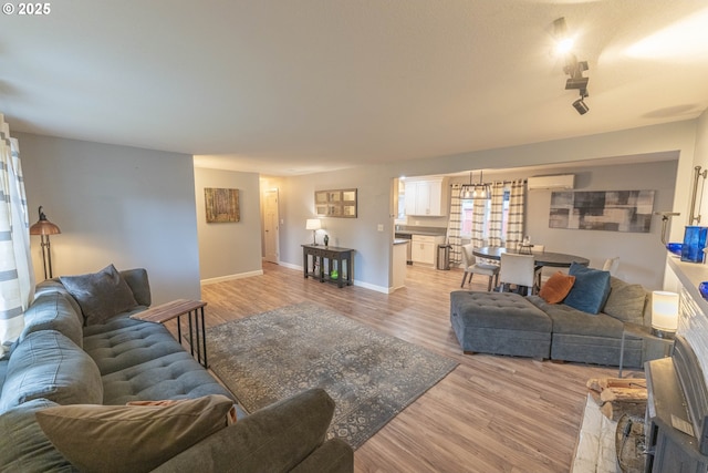 living room featuring a wall mounted air conditioner and light hardwood / wood-style flooring