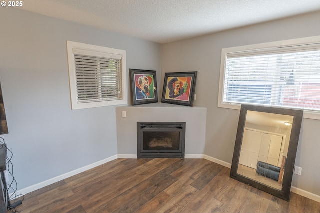 unfurnished living room featuring dark wood-type flooring and a textured ceiling