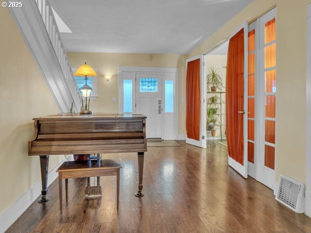 living area featuring visible vents, baseboards, and wood finished floors