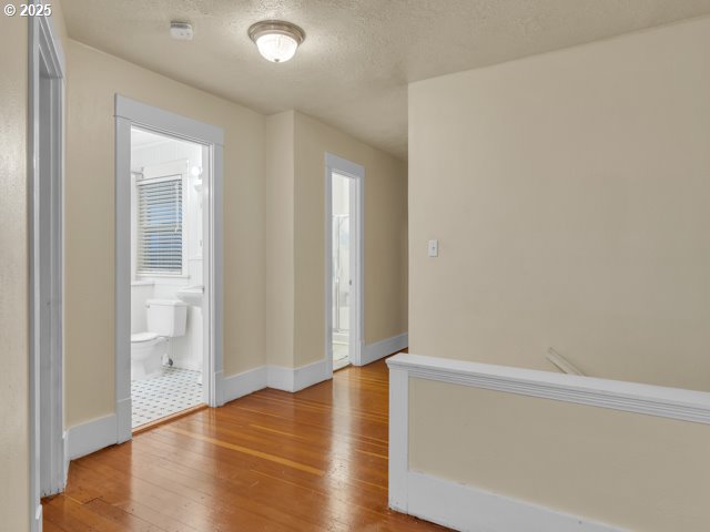 unfurnished room featuring baseboards, a textured ceiling, and light wood finished floors