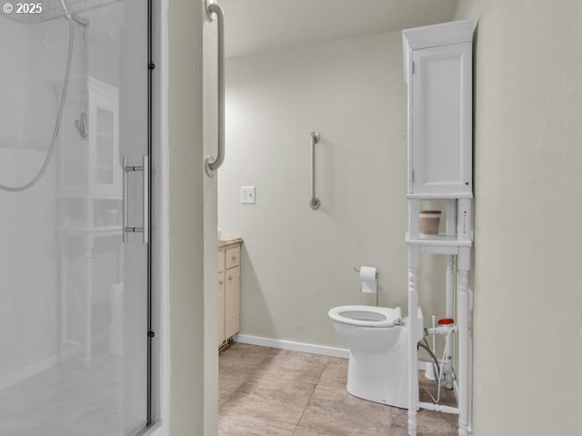 bathroom featuring toilet, walk in shower, vanity, and baseboards