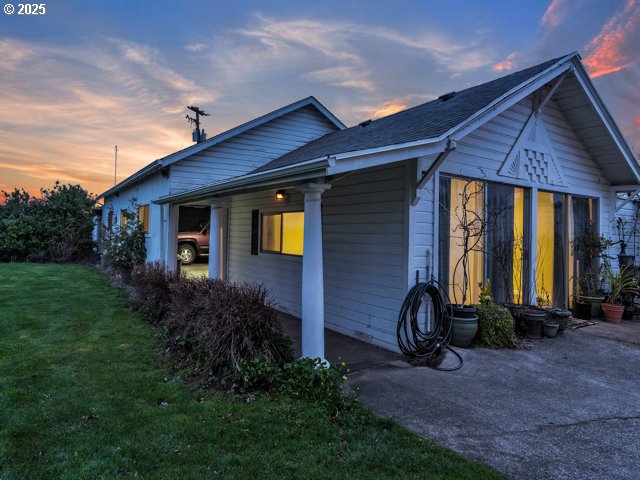 property exterior at dusk featuring a lawn