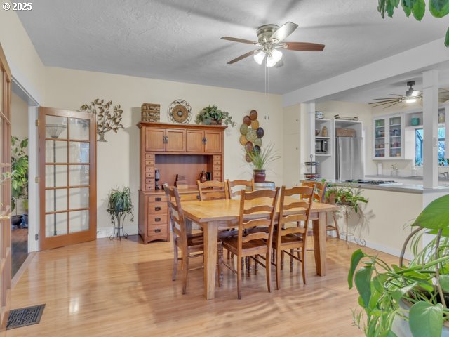 dining room featuring a textured ceiling, light wood-type flooring, visible vents, and ceiling fan