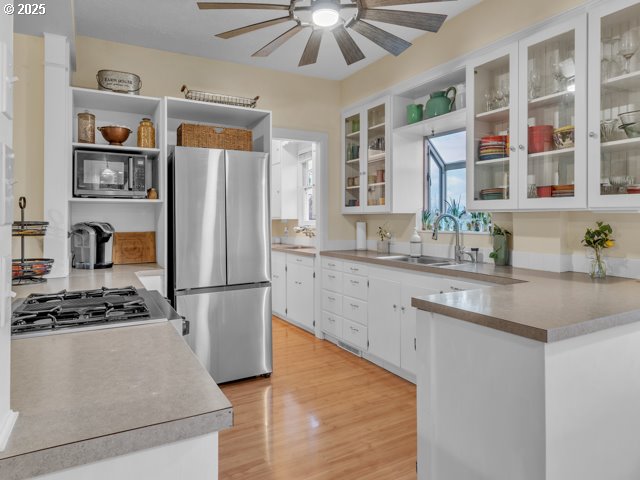 kitchen featuring a sink, open shelves, white cabinetry, appliances with stainless steel finishes, and ceiling fan