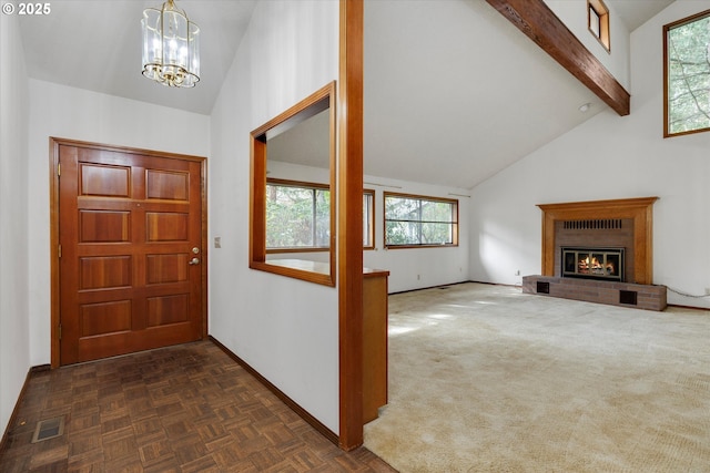 entryway with baseboards, beam ceiling, a chandelier, high vaulted ceiling, and a brick fireplace