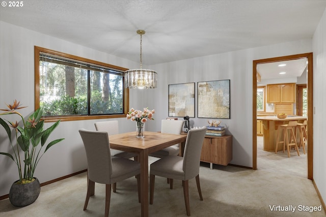 dining room featuring a chandelier, light carpet, and baseboards