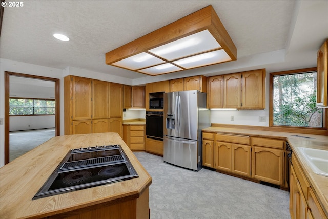 kitchen featuring black appliances, wooden counters, light colored carpet, a textured ceiling, and recessed lighting