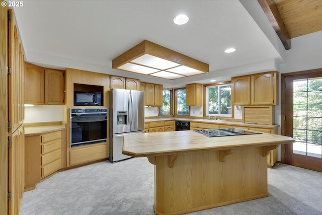 kitchen featuring black appliances, light colored carpet, butcher block counters, a breakfast bar area, and a sink
