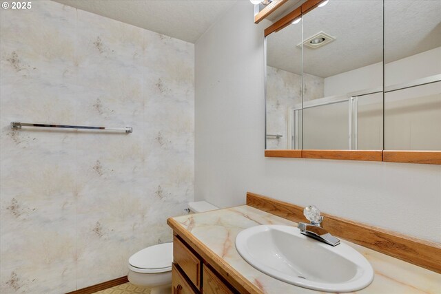 bathroom with a stall shower, toilet, and vanity