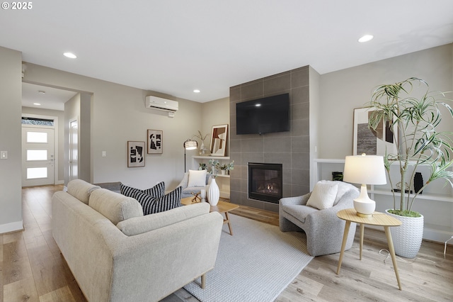 living room with light wood-type flooring, a fireplace, recessed lighting, and a wall mounted AC