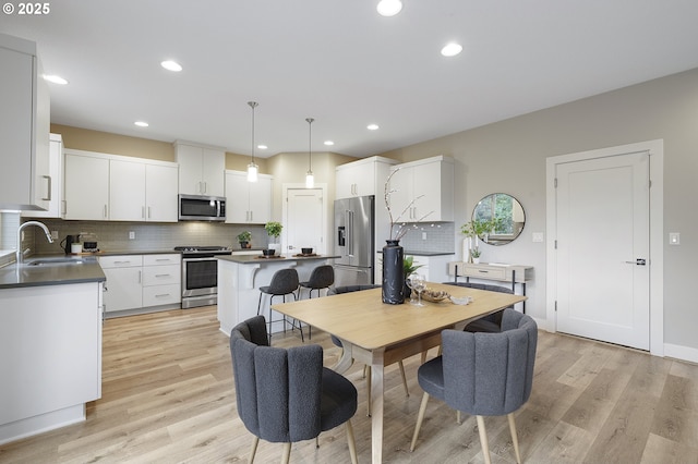 dining room with light wood finished floors, baseboards, and recessed lighting