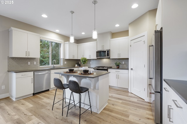 kitchen featuring dark countertops, white cabinetry, stainless steel appliances, and a sink