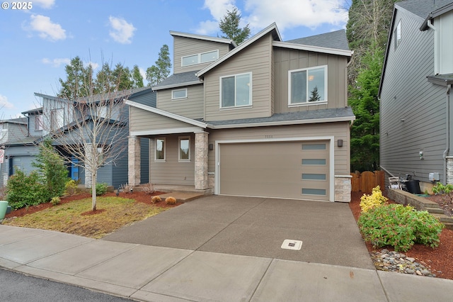 view of front facade with a shingled roof, concrete driveway, stone siding, an attached garage, and board and batten siding