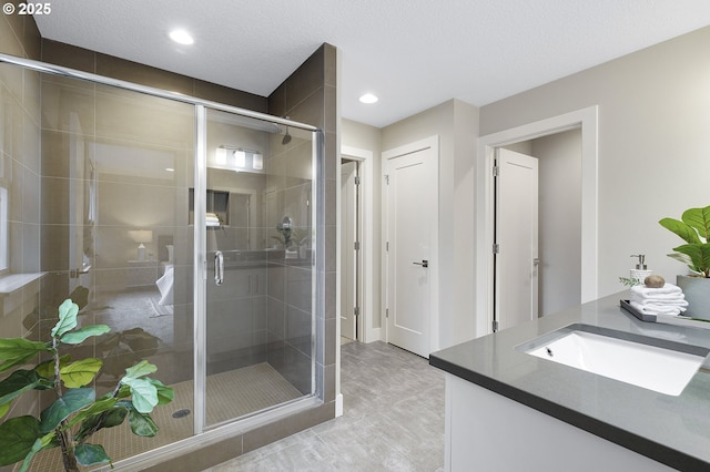 full bathroom with a stall shower, vanity, a textured ceiling, and recessed lighting